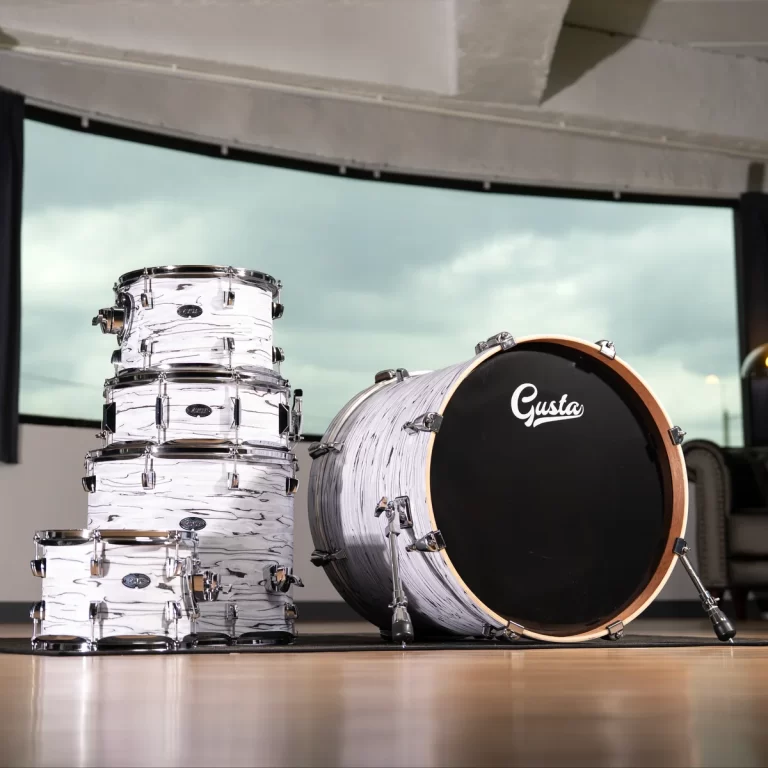 Stack of white marble-pattern drum shells arranged beside a large black-headed bass drum in a studio setting, with a window in the background. ขายราคาพิเศษ