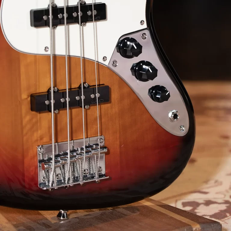 Close-up of a sunburst electric bass guitar body showing pickups, control knobs, and chrome bridge. ขายราคาพิเศษ
