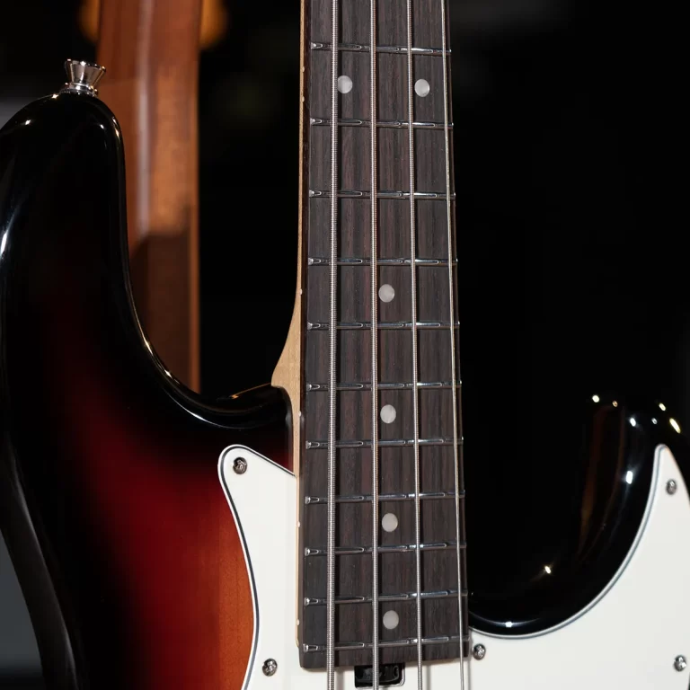 Close-up of a sunburst electric guitar neck with metal frets and strings over a dark fretboard, white pickguard visible on the body ขายราคาพิเศษ