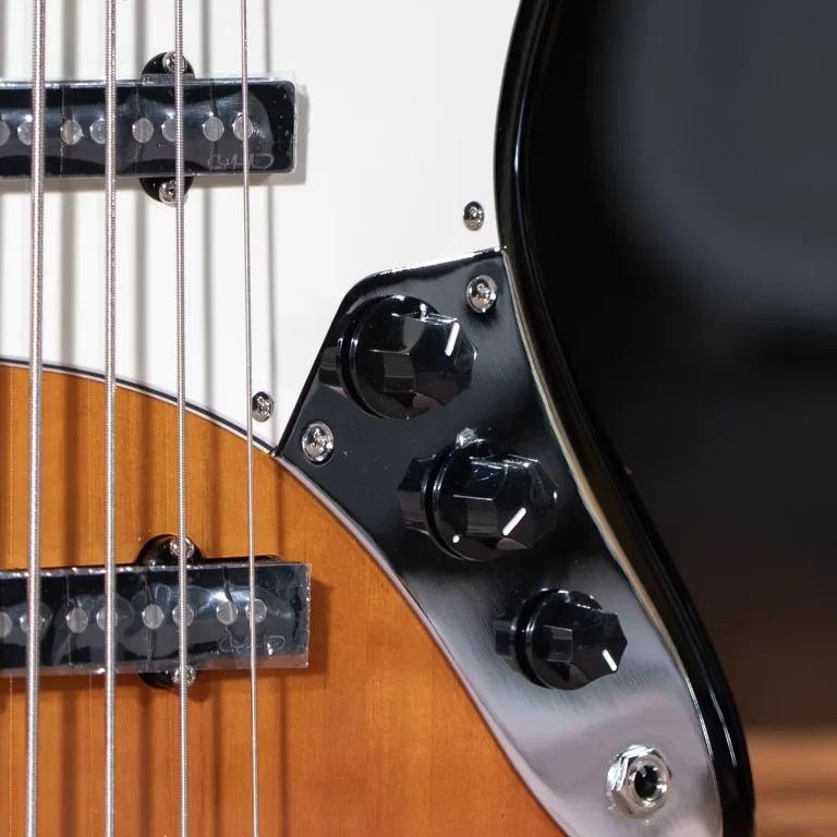 Close-up of an electric guitar body showing chrome control plate, black knobs, strings, and a sunburst finish edge. ขายราคาพิเศษ