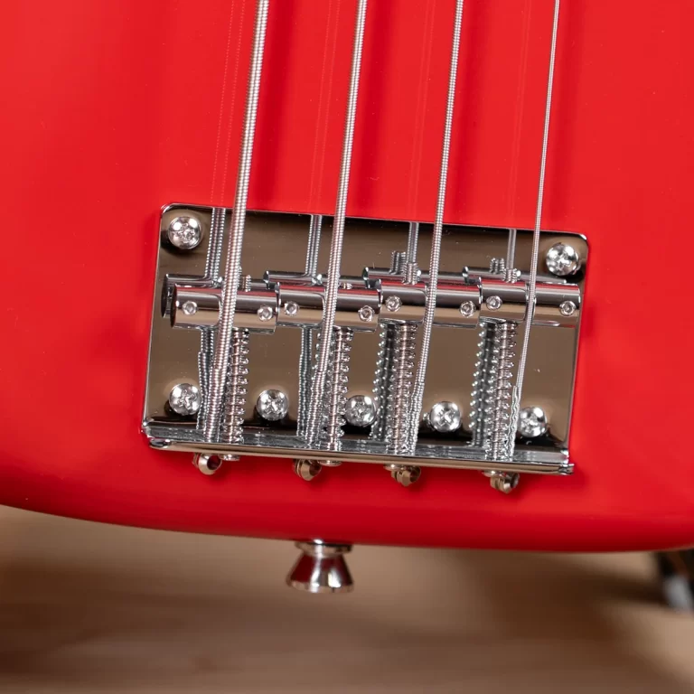 Close-up of a chrome guitar bridge on a red electric guitar with six strings and saddles ขายราคาพิเศษ