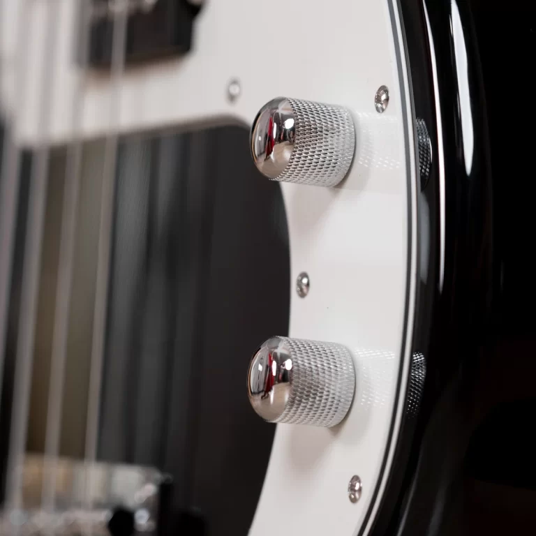 Close-up of chrome guitar knobs on a white pickguard of an electric guitar ขายราคาพิเศษ
