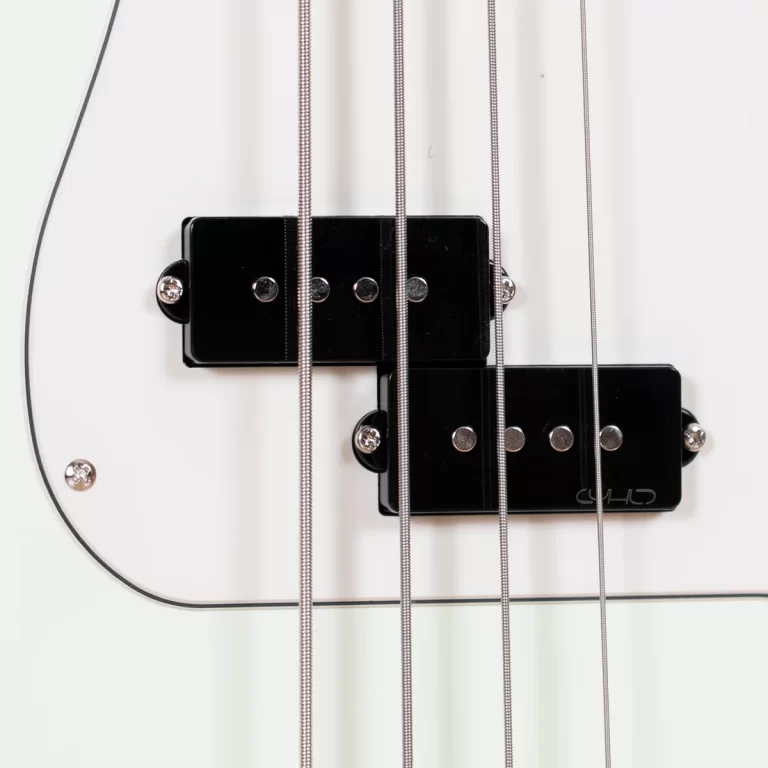 Close-up of two glossy black humbucker pickups on a white electric guitar, with six metal strings crossing over them. ขายราคาพิเศษ