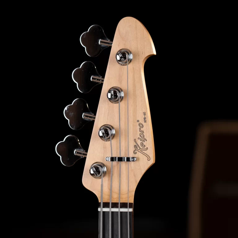 Headstock of a wooden guitar with tuner pegs and strings, logo visible on the headstock against a dark background ขายราคาพิเศษ