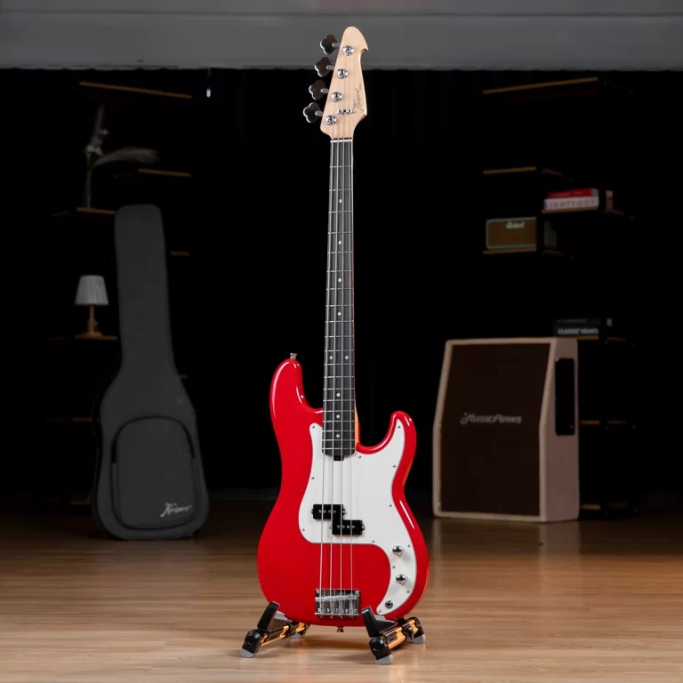 Red electric bass guitar on a stand in a dim studio with an amplifier and gear cases in the background. ขายราคาพิเศษ