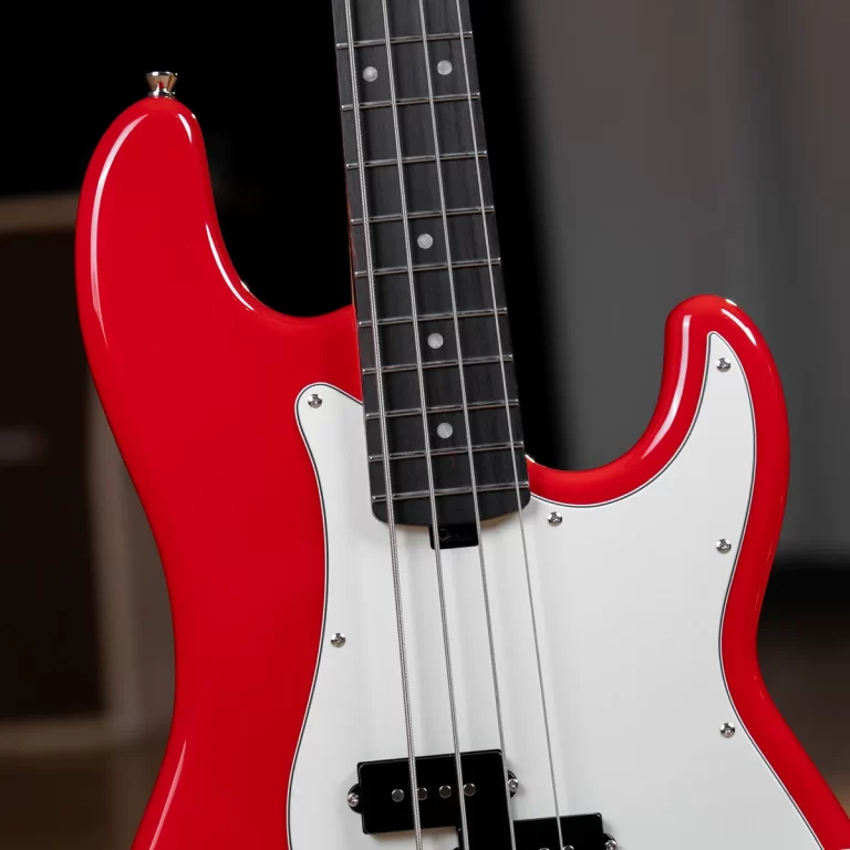 Close-up of a red electric bass guitar with a white pickguard, showcasing the neck, strings, and pickups against a dark background. ขายราคาพิเศษ