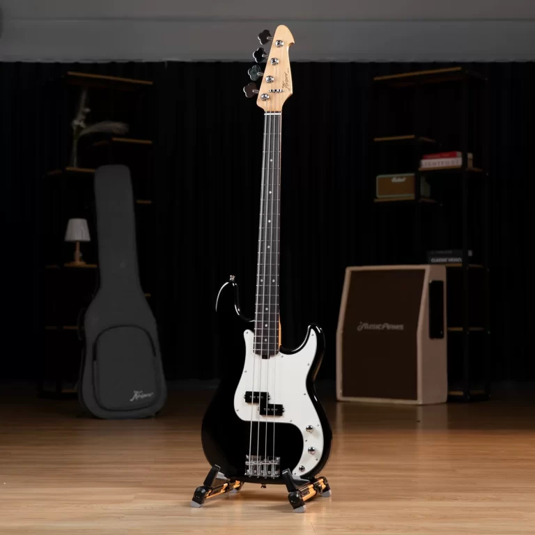 Black electric bass guitar on a stand in a dim music studio with a guitar case and amp gear in the background, centered on a wooden floor. ขายราคาพิเศษ