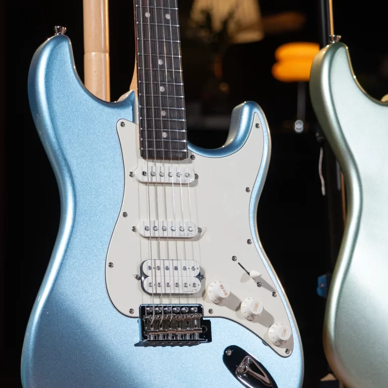 Blue metallic Stratocaster-style electric guitar with white pickguard and three pickups on display. ขายราคาพิเศษ