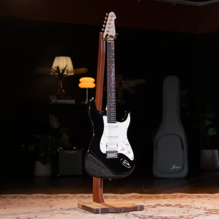 Black electric guitar on a wooden stand in a dimly lit room with a guitar case in the background. ขายราคาพิเศษ