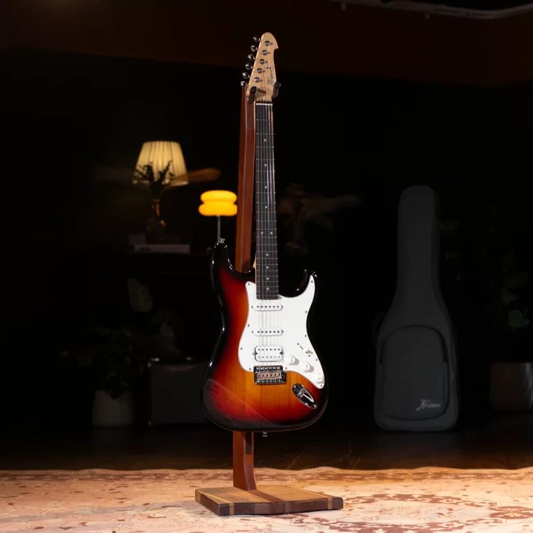 Sunburst Fender Stratocaster on a wooden stand in a dimly lit room with a lamp in the background. ขายราคาพิเศษ