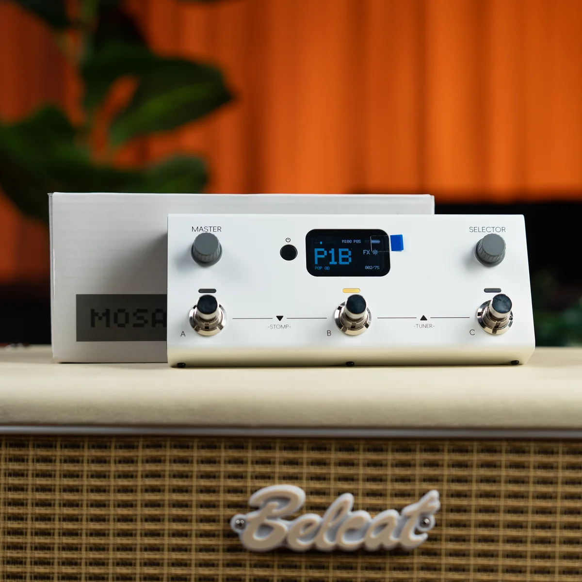 White guitar effects processor with LCD screen showing P18, three footswitches labeled A, B, C, and two knobs on a speaker cabinet top.