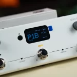 Close-up of a white guitar effects unit with a blue digital display showing 'P18' and labeled knobs like STOMP and TUNER on the panel. ขายราคาพิเศษ
