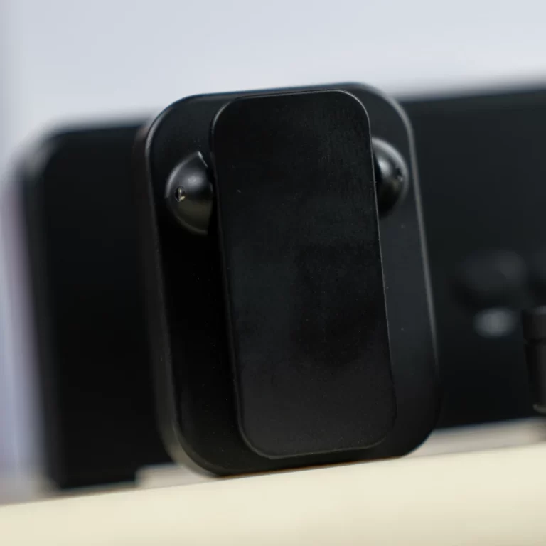 Close-up of a black car phone mount holder clipped to a dashboard or stand, showing the adjustable cradle and mounting arm. ขายราคาพิเศษ