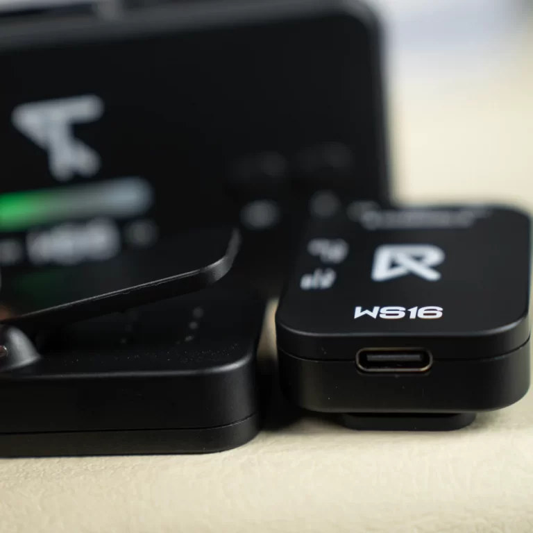 Close-up of a small black WS16 USB-C dongle with a white logo, resting on a light surface beside another device. ขายราคาพิเศษ