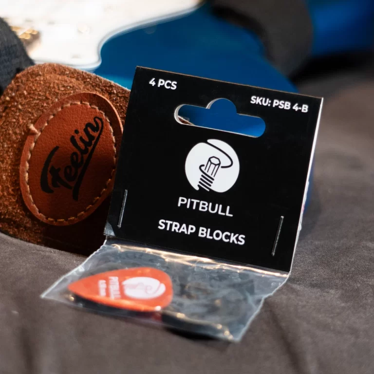 Black packaging for Pitbull strap blocks (4 pieces) with logo, placed on dark fabric next to a brown leather patch with 'Freedom' stitched in. ขายราคาพิเศษ