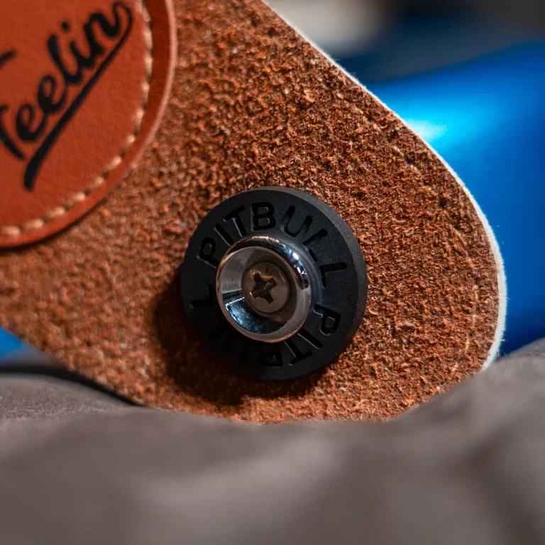 Close-up of a brown suede belt/strap with a black circular fastener and a shiny metal screw at its center. ขายราคาพิเศษ