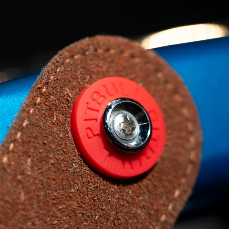 Macro shot of a red circular pull tab with the word PULL, mounted on a brown textured surface with a blue background edge. ขายราคาพิเศษ