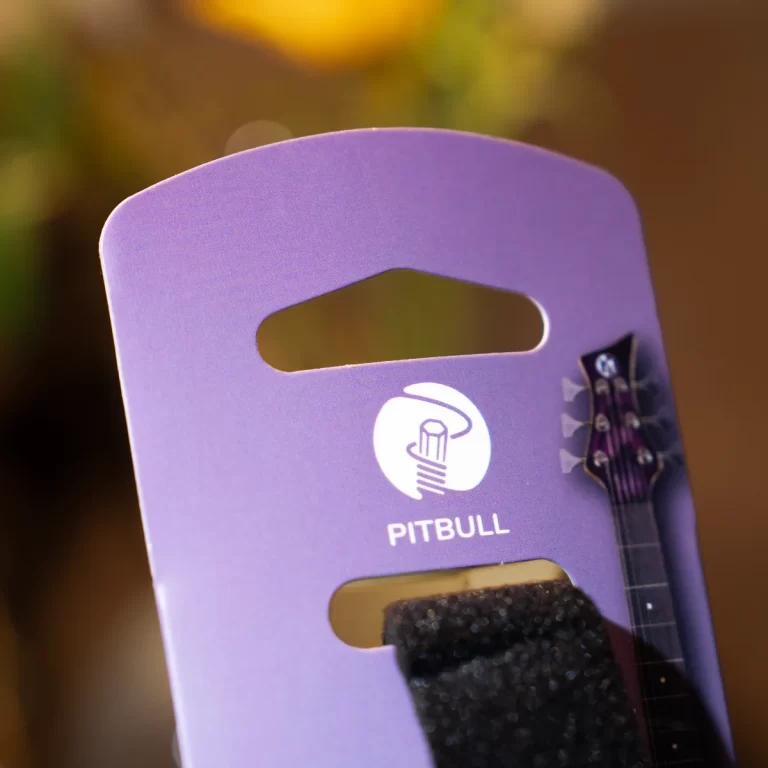 Close-up of a purple Pitbull branded guitar stand with a cutout handle and a guitar neck visible at the right. ขายราคาพิเศษ