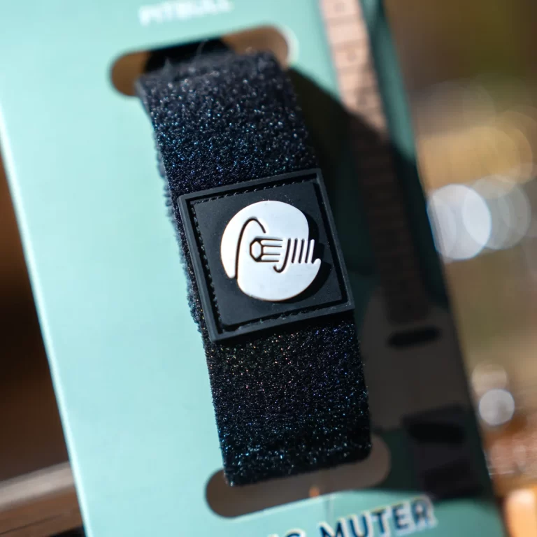 Close-up of a glittery black strap with a square badge showing an NFC/contactless icon on turquoise packaging. ขายราคาพิเศษ