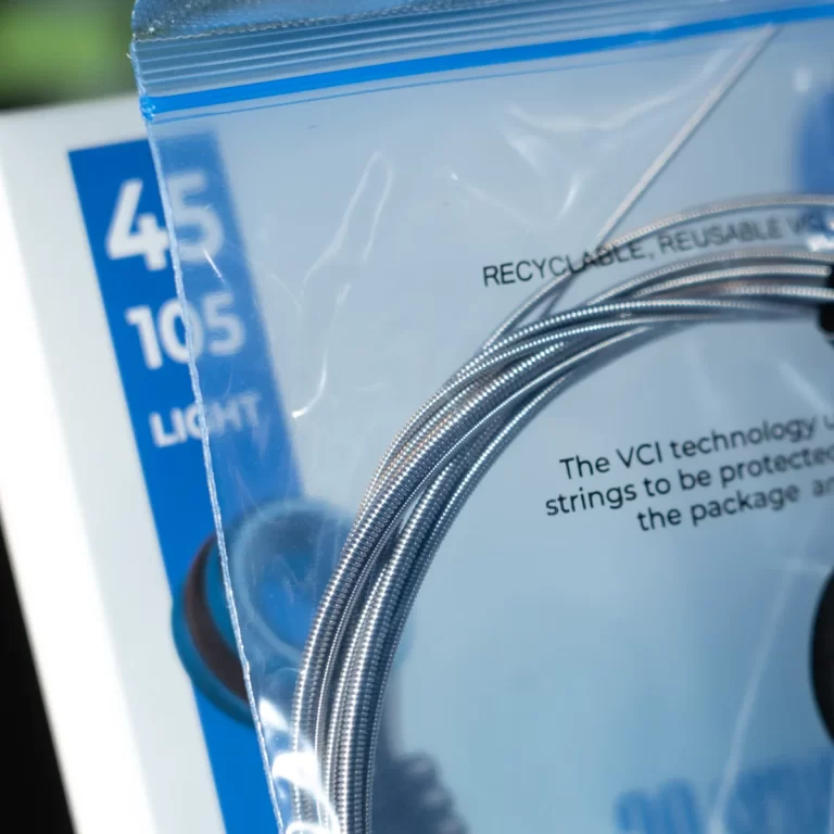 Close-up of a metal braided cable coil in clear packaging, with 'RECYCLABLE' and blue label visible in the background. ขายราคาพิเศษ