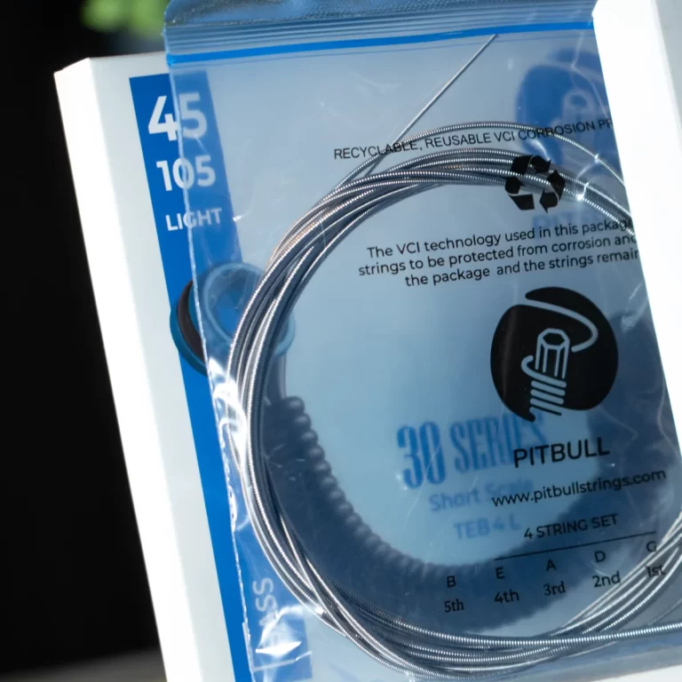 Close-up of a packaged 4-string guitar/string set labeled Pitbull, with coiled steel strings visible in a clear bag. ขายราคาพิเศษ