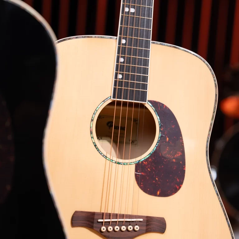 Close-up of an acoustic guitar showing the light wood body, soundhole, tortoiseshell pickguard, strings, and part of the fretboard. ขายราคาพิเศษ