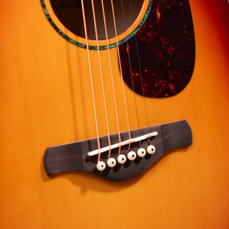 Close-up of an acoustic guitar showing the bridge, six strings, and round sound hole. ขายราคาพิเศษ