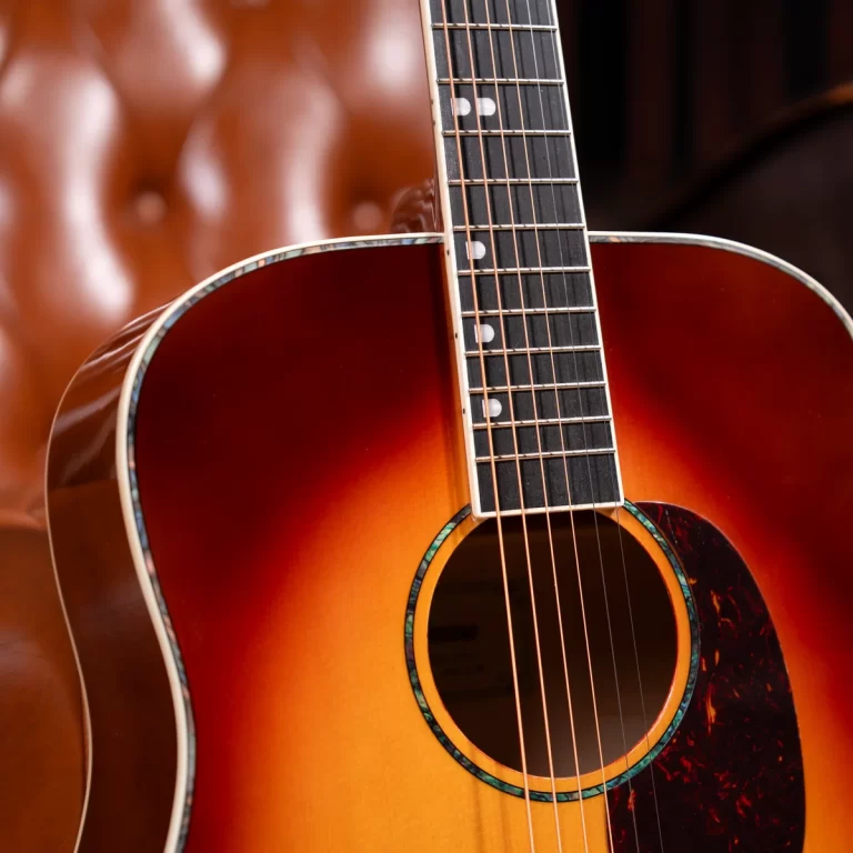 Close-up of a sunburst acoustic guitar body and fretboard, showing strings and soundhole with a marbled pickguard outline to the right. ขายราคาพิเศษ