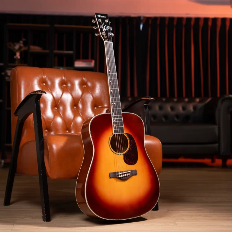 Sunburst acoustic guitar resting against a brown tufted chair in a cozy lounge setting. ขายราคาพิเศษ