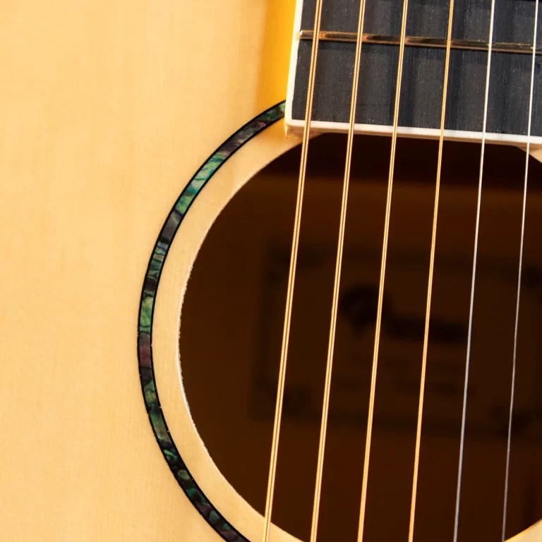 Close-up of an acoustic guitar soundhole with strings crossing the opening and decorative binding along the edge. ขายราคาพิเศษ