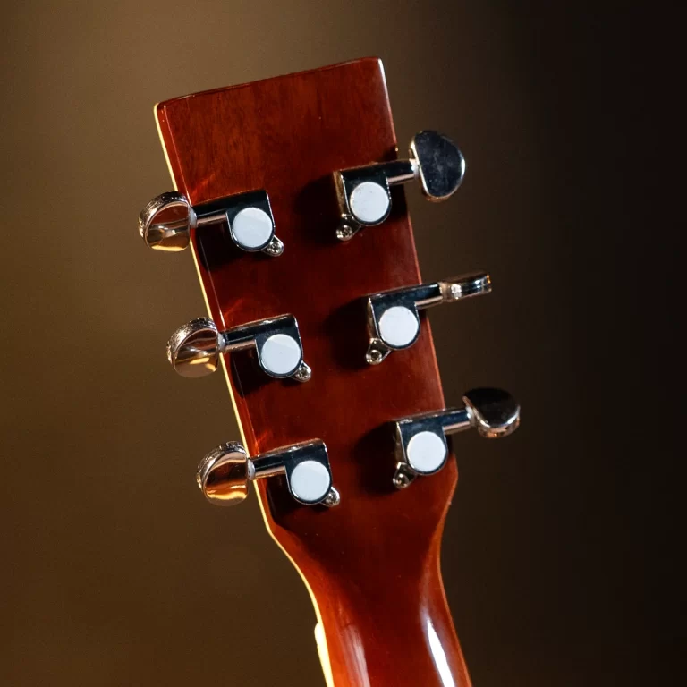 Close-up of a guitar headstock with six silver tuning pegs on a glossy reddish-brown neck, warm lighting ขายราคาพิเศษ
