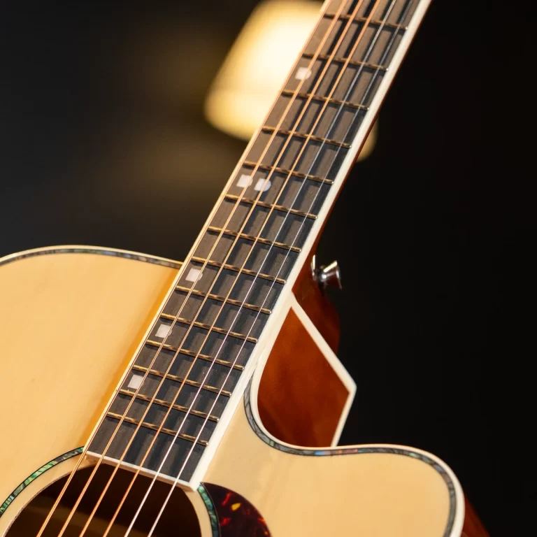 Close-up of an acoustic guitar neck and fretboard with strings visible ขายราคาพิเศษ