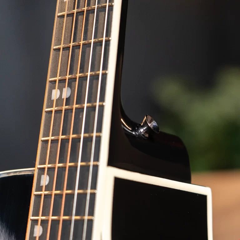 Close-up of a guitar neck showing frets and copper strings against a dark body. ขายราคาพิเศษ