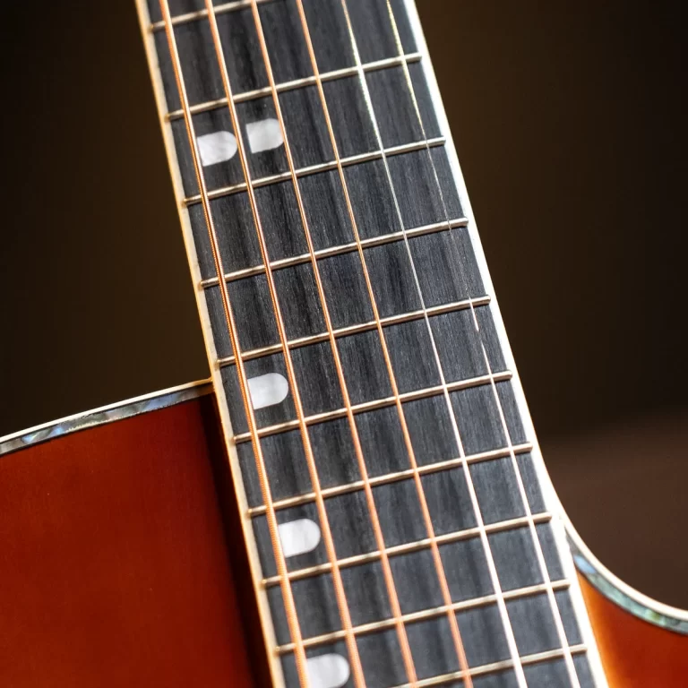 Close-up of a guitar neck showing frets, strings, and fretboard inlays against a dark background. ขายราคาพิเศษ