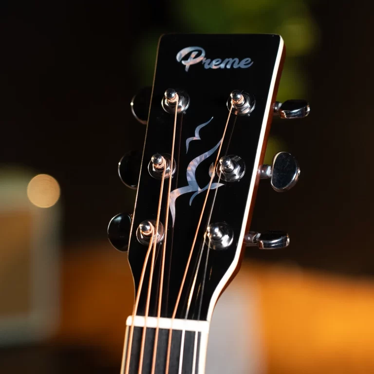 Close-up of a black guitar headstock with six tuning pegs, thin strings, and a flame inlay; brand name 'Preme' visible on the headstock ขายราคาพิเศษ