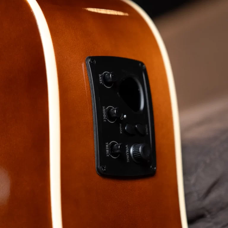 Close-up of a sunburst acoustic guitar body showing the black built-in preamp control panel with knobs labeled Bass, Mid, Treble, and Volume on a wooden finish. ขายราคาพิเศษ