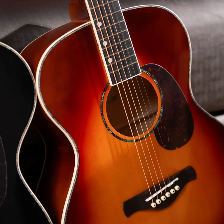 Close-up of an acoustic guitar showing orange sunburst body, soundhole, and six strings. ขายราคาพิเศษ