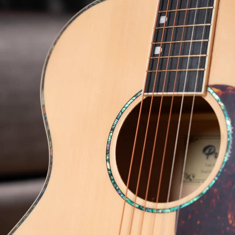 Close-up of an acoustic guitar body showing the soundhole, strings, and abalone binding detail on the edge of the body. ขายราคาพิเศษ