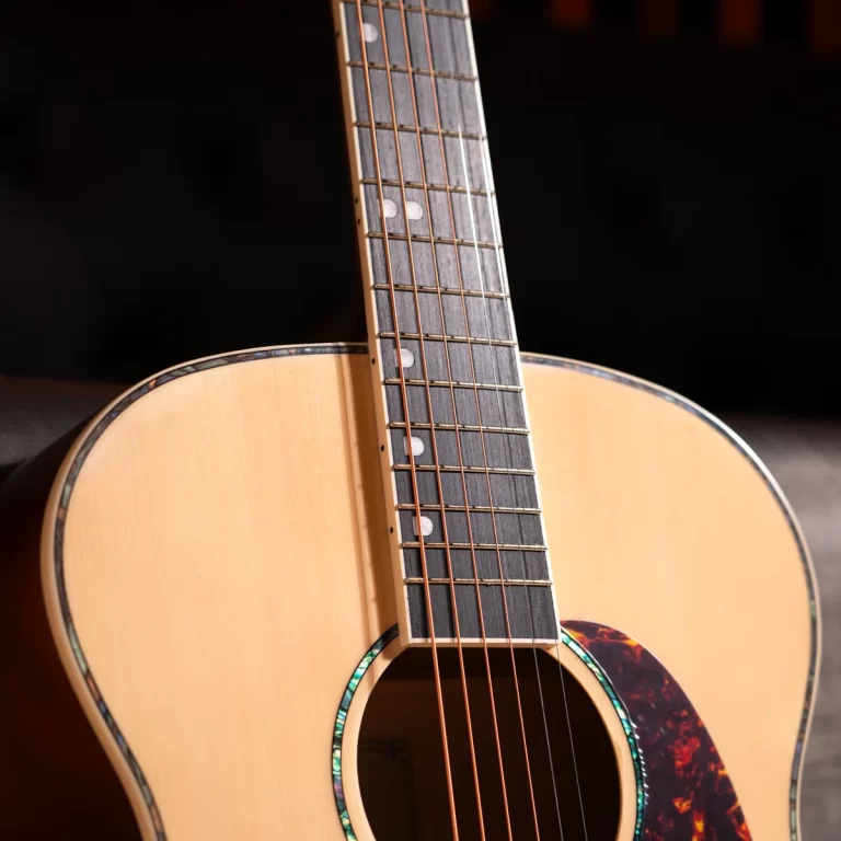 Close-up of an acoustic guitar neck resting on the body, showing frets, fret markers, and six strings over the sound hole. ขายราคาพิเศษ