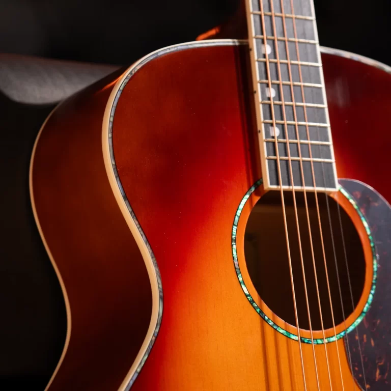 Close-up of a sunburst acoustic guitar body with strings and fretboard visible, highlighting the circular sound hole rim. ขายราคาพิเศษ