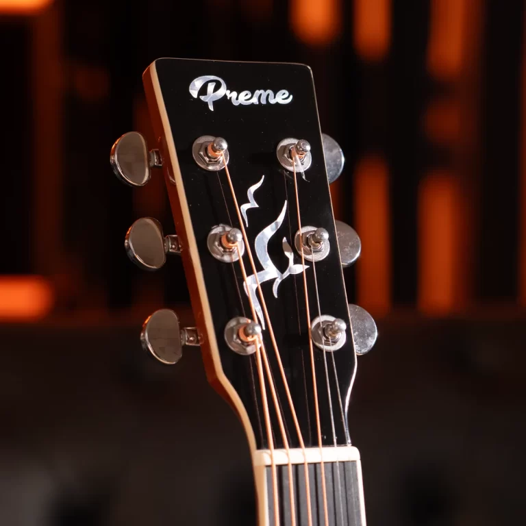 Close-up of a black guitar headstock with six tuning pegs and strings, featuring a white logo. ขายราคาพิเศษ