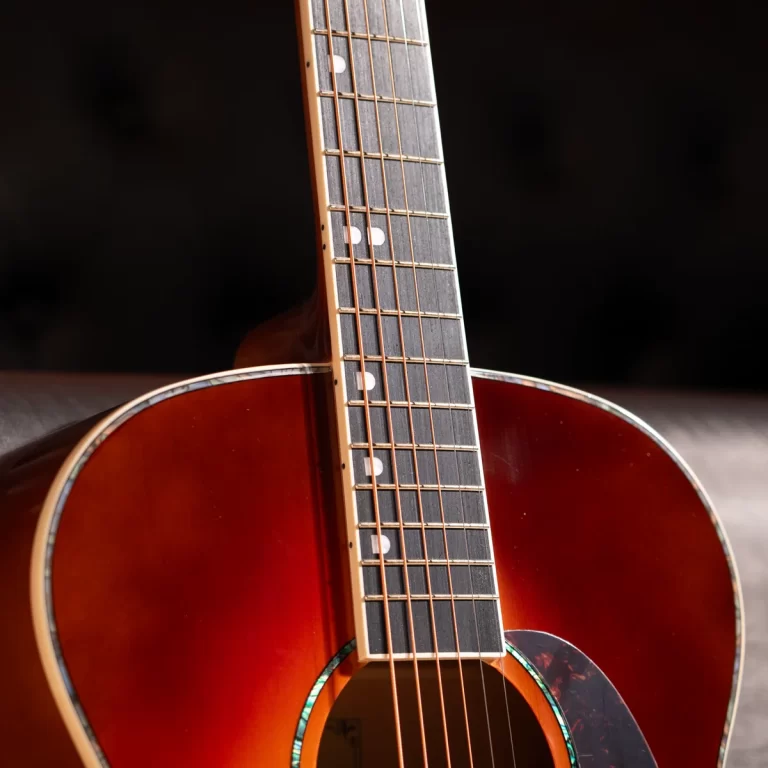 Close-up of an acoustic guitar neck and body with a sunburst finish, frets and dot inlays in focus. ขายราคาพิเศษ