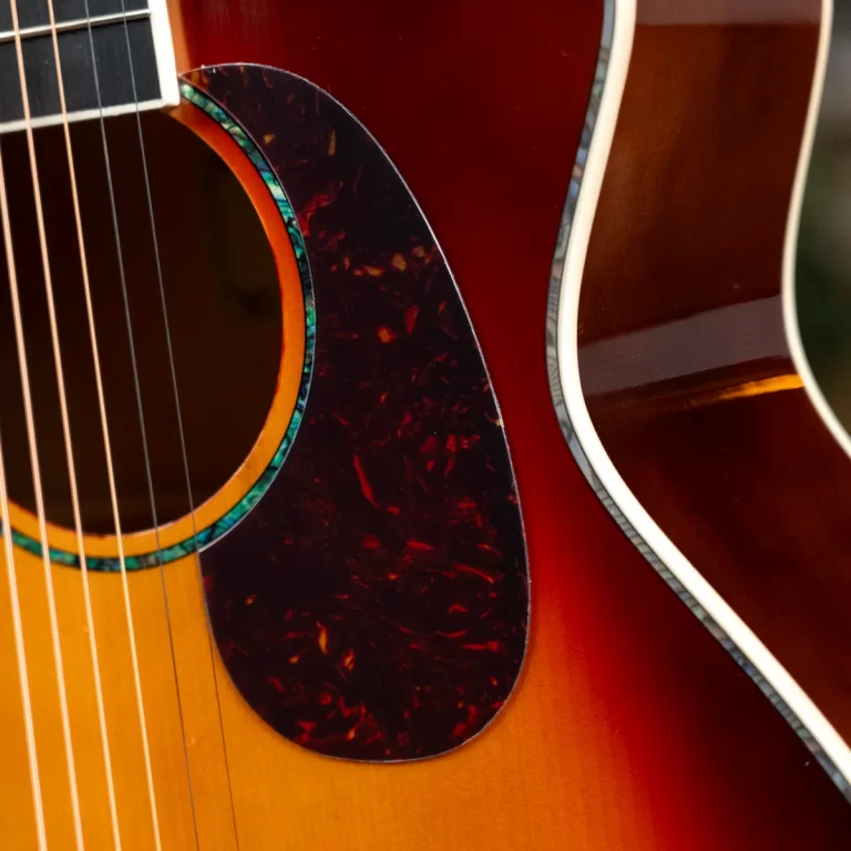 Close-up of two acoustic guitars showing strings, pickguard, and sunburst body finish. ขายราคาพิเศษ