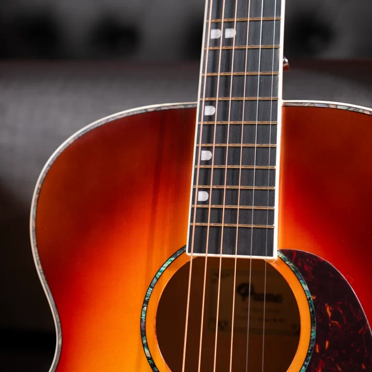 Close-up of an acoustic guitar showing the sunburst body, fretboard, and six strings along the neck. ขายราคาพิเศษ
