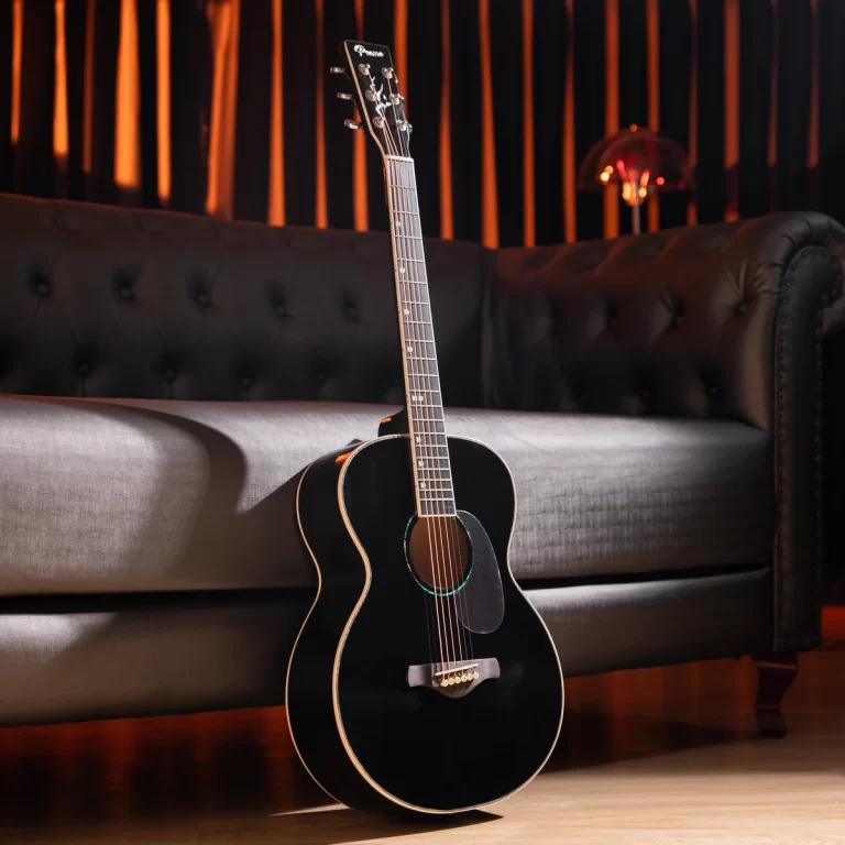 Black acoustic guitar resting upright against a tufted leather sofa in a dimly lit lounge set. ขายราคาพิเศษ