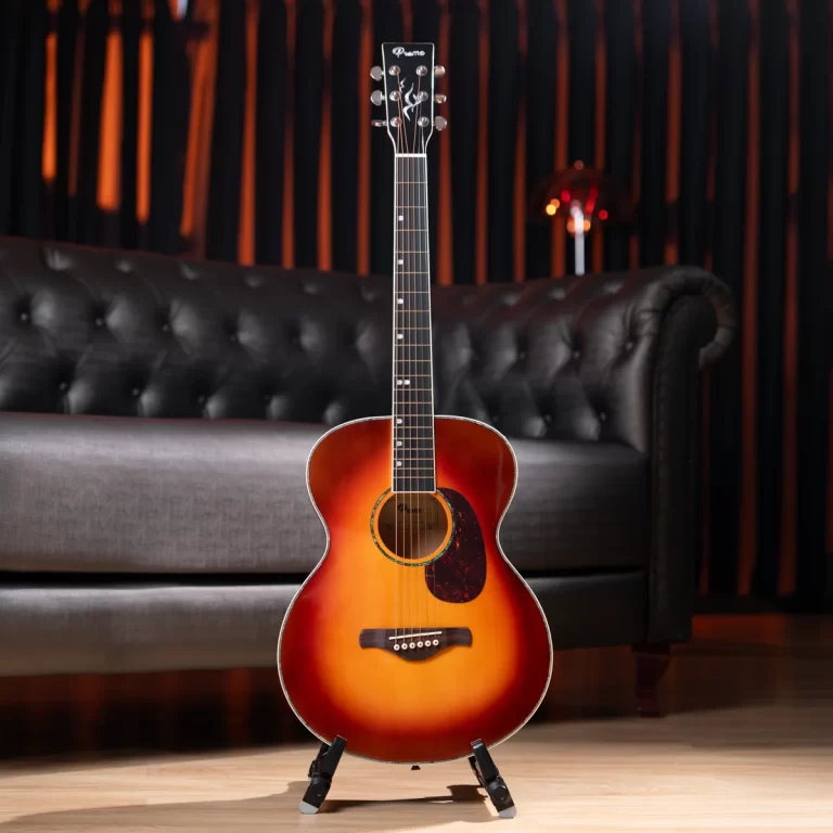 Sunburst acoustic guitar on a stand in a cozy studio living room setting with a tufted sofa in the background. ขายราคาพิเศษ
