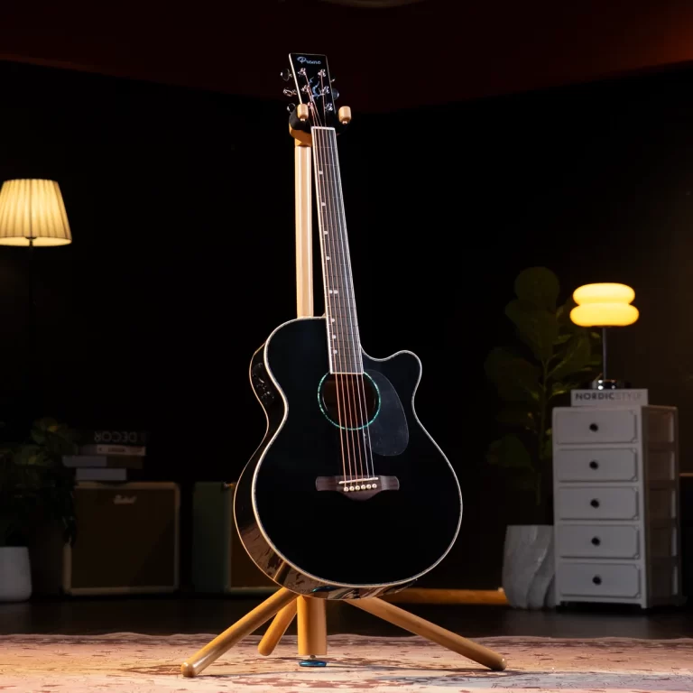 Black acoustic guitar on a wooden stand in a dimly lit studio with warm lamps in the background. ขายราคาพิเศษ