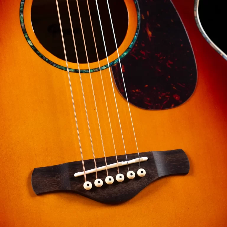 Close-up of an acoustic guitar showing six strings over the bridge and soundhole on a sunburst body ขายราคาพิเศษ