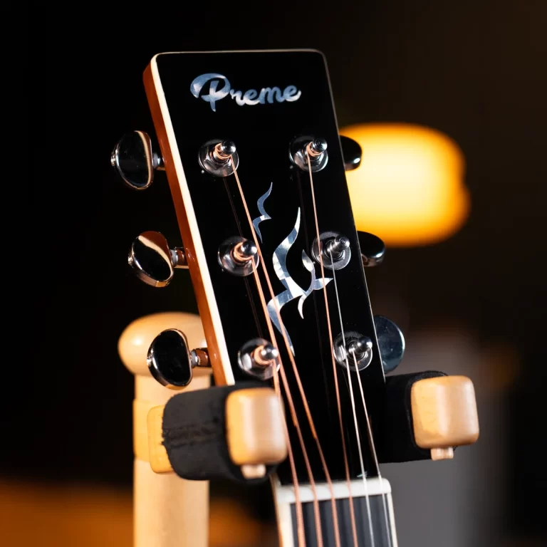 Close-up of a black guitar headstock with tuning pegs and strings, featuring a 'Preme' logo on the headstock. ขายราคาพิเศษ