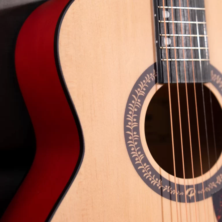 Close-up of an acoustic guitar showing the soundhole, decorative rosette, and strings on a light wood body. ขายราคาพิเศษ